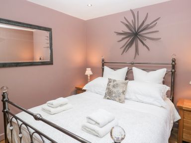 A bedroom with a bed and side table at Corner Cottage in Troutbeck