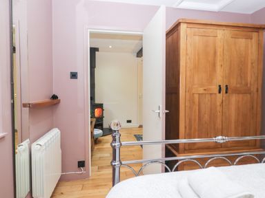 A bedroom with a wardrobe and a door at Corner Cottage in Troutbeck