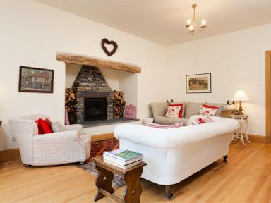 A living room with a stone fireplace sofas armchair and wooden floor at The Old Coach House in Troutbeck
