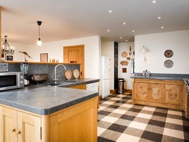 A kitchen with checkered floor wooden cabinets and various appliances at The Old Coach House in Troutbeck