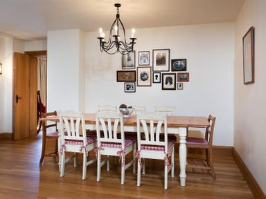 A dining room with a wooden table and eight chairs with cushions and pictures on the wall at The Old Coach House in Troutbeck