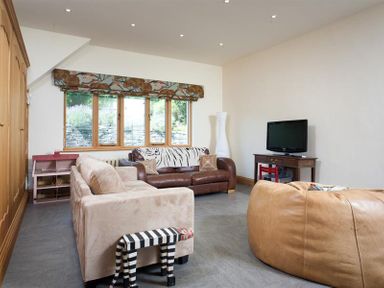 A living room with sofas a television and a window with patterned valance at The Old Coach House in Troutbeck