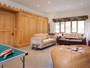 A living room with two sofas a large bean bag a ping pong table and wooden wardrobes at The Old Coach House in Troutbeck