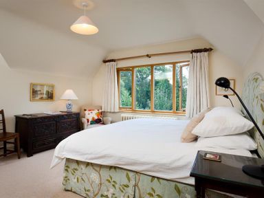 A bedroom with a bed beside a window and a chair near a wooden cabinet at The Old Coach House in Troutbeck
