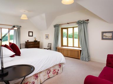 A bedroom with a bed table lamp chest of drawers chairs and curtains at The Old Coach House in Troutbeck