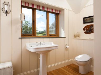 A bathroom with a pedestal sink a window and a toilet at The Old Coach House in Troutbeck