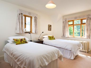 A bedroom with two single beds and windows with curtains at The Old Coach House in Troutbeck