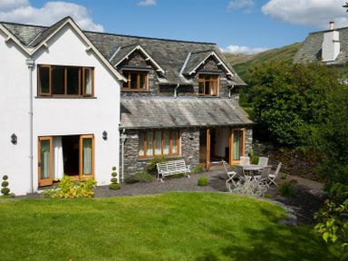 A garden with outdoor seating and a mix of stone and white walls on a house at The Old Coach House in Troutbeck