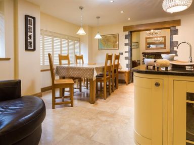 A dining area with a wooden table and six chairs covered by a polka dot tablecloth at Oaklea Ambleside