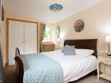 A bedroom with a wooden bed a blue patterned bedspread nightstands with lamps a window and a double closet at Oaklea Ambleside