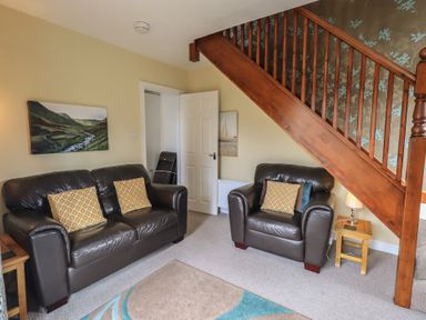 A living room with a sofa and armchair at A River Runs By in Staveley