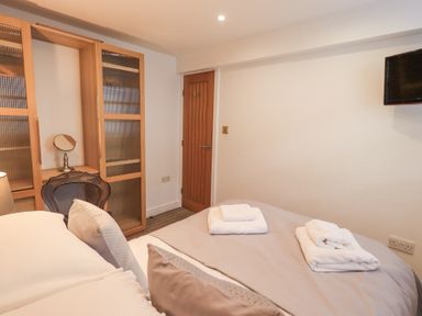 A bedroom with a bed covered with towels a wooden door and a wall-mounted TV at Workshop Cottage in Bowness