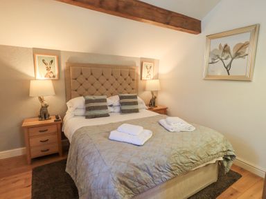 A bedroom with a double bed two bedside tables with lamps and bunny decorations at Workshop Cottage in Bowness
