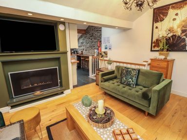 A living room with a sofa and fireplace at Workshop Cottage in Bowness