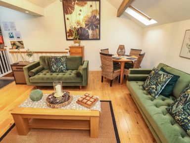 A living room with sofas and a dining area at Workshop Cottage in Bowness
