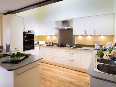 A kitchen with white cabinets pots on stove and a bowl of vegetables at Lakefield House in Hawkshead