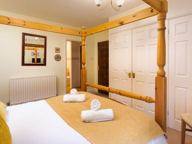 A bedroom with a wooden four-poster bed and folded towels on the bed at Lakefield House in Hawkshead