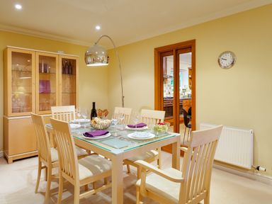 A dining room with a glass table set for six and a wooden cabinet at Merewood Lodge in Ambleside