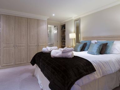 A bedroom with a bed folded towels and built in wardrobes at Merewood Lodge in Ambleside
