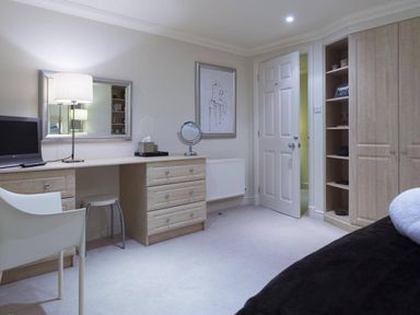 A bedroom with a desk lamp mirror computer chair and wardrobe at Merewood Lodge Ambleside