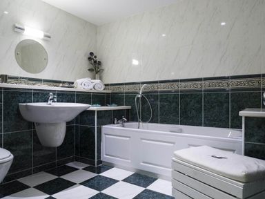 A bathroom with a bathtub sink mirror and towels at Merewood Lodge Ambleside