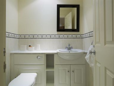 A bathroom with a toilet sink mirror and cabinet at Merewood Lodge Ambleside
