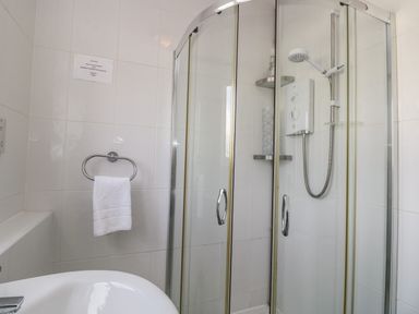 A bathroom with a corner shower enclosure a towel ring with a white towel and a sink at The Heights in Bowness