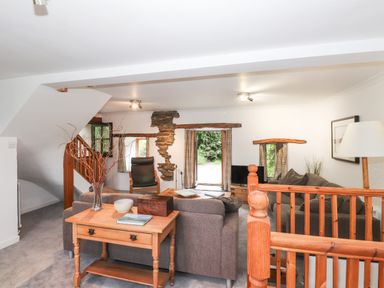 A living room with sofas a wooden table a chair and a television at Cherry Tree Cottage at Satterthwaite in Hawkshead