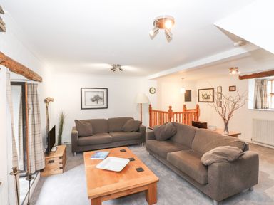 A living room with two brown sofas a wooden coffee table and framed pictures on the wall at Cherry Tree Cottage at Satterthwaite Hawkshead