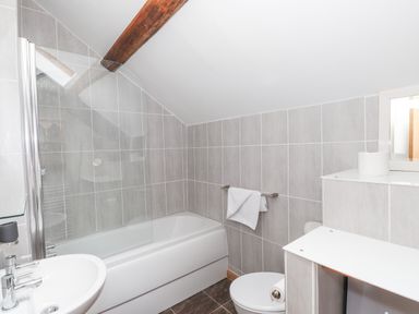 A bathroom with a bathtub a sink a toilet and towels at Cherry Tree Cottage at Satterthwaite in Hawkshead