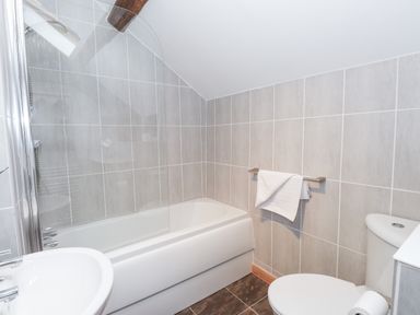 A bathroom with a bathtub shower combination a sink and a toilet at Cherry Tree Cottage at Satterthwaite in Hawkshead