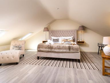 A bedroom with a bed and two bedside lamps a chaise lounge and a table lamp at Old Wool Loft in Ambleside