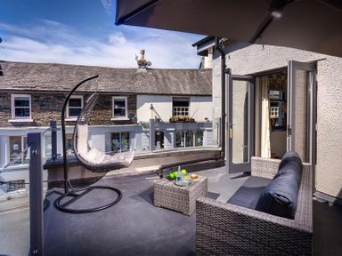 A balcony with a hanging chair sofa and small table at Old Wool Loft in Ambleside