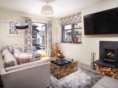 A living room with a grey sofa cushions and a glass coffee table with a stone base at Old Wool Loft in Ambleside