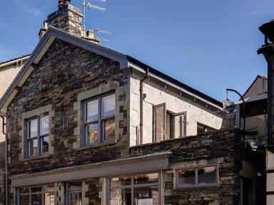 Exterior of a stone building with windows and a balcony with a hanging chair at Old Wool Loft Ambleside