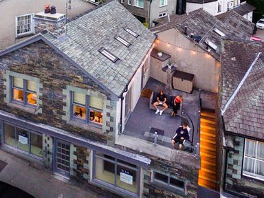 An outdoor terrace with seating and stairs in a stone building at Old Wool Loft Ambleside
