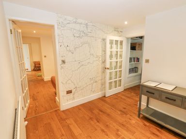 A hallway with wooden flooring a small console table and doors leading to adjoining rooms at Home Farm House in Penrith