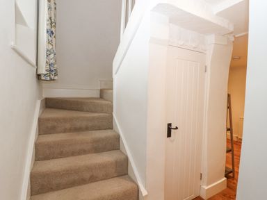 A carpeted staircase next to a white door in a hallway at Home Farm House in Penrith
