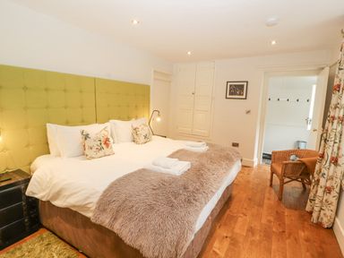 A bedroom with a large bed with green headboard and floral pillows at Home Farm House in Penrith