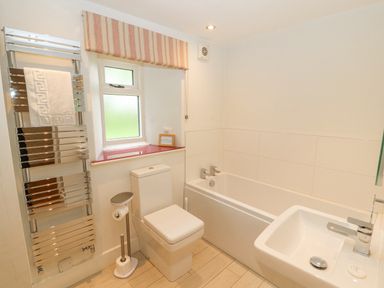 A bathroom with a bathtub toilet sink heated towel rack and a window at Home Farm House in Penrith