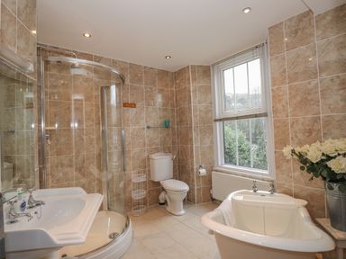 A bathroom with a shower cubicle toilet bathtub sink and window with blinds at Fernleigh Cottage in Ambleside