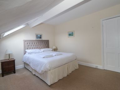 A bedroom with a double bed two bedside tables with lamps a door and two framed pictures at Fernleigh Cottage in Ambleside
