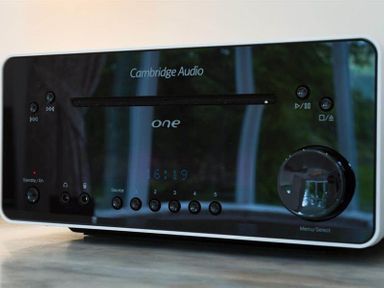 A black Cambridge Audio One music player with buttons and a large knob on a wooden surface