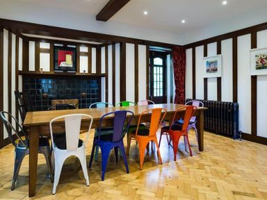 A dining room with a long wooden table and colorful metal chairs at Loughrigg Cottage in Ambleside