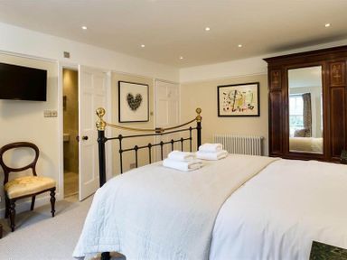 A bedroom with a bed towels and a wooden wardrobe in Loughrigg Cottage Ambleside