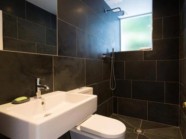 A bathroom with a sink, toilet, shower, and a frosted window at Loughrigg Cottage in Ambleside