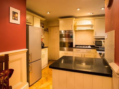 A kitchen with white cabinets black countertops a refrigerator oven stove and microwave at Priory Lodge in Windermere