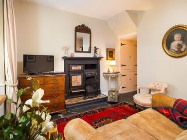 A living room with a fireplace television chest of drawers rug and sofa at The Blithe Hare in Troutbeck Bridge