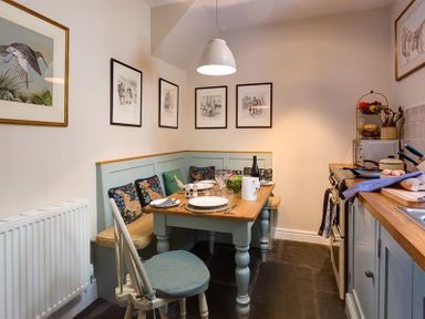 A kitchen dining area with a corner bench seating and table set for a meal at The Blithe Hare in Troutbeck Bridge