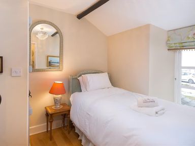 A bedroom with a single bed bedside table lamp and wall mirror at The Blithe Hare in Troutbeck Bridge